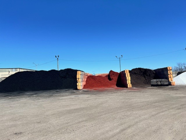 Front-end loader scooping mulch at the Omni Landscape & Garden Supply yard at sunset